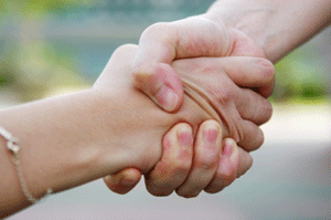 Two people shake hands or help one another up