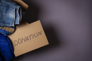 Cardboard box labelled donation with jeans and other items piled atop