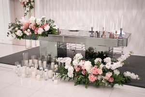Main table at a wedding reception with beautiful wedding decorations including candles in candlesticks, candles in glass vases, and beautiful floral arrangements